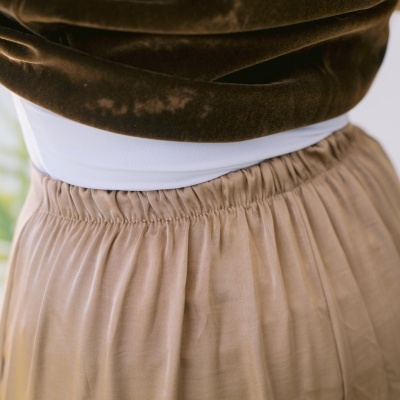 Detalhe da parte inferior da camisola castanha e saia bege com cintura elástica