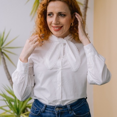 Mulher com camisa branca e calças de ganga junto a plantas