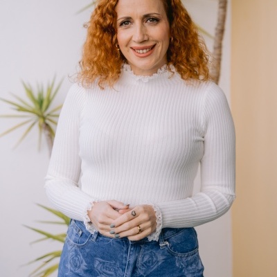 Mulher com camisola branca de malha e calças jeans azuis com padrão floral