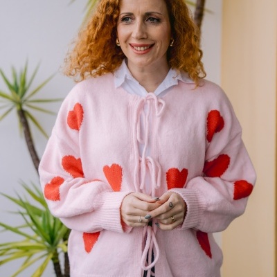 Casaco rosa com corações vermelhos e laços, camisa branca e calças de ganga azuis