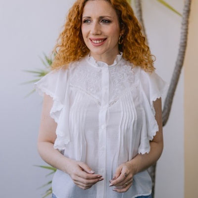 Blusa branca bordada com renda e babados, combinada com jeans azul claro.
