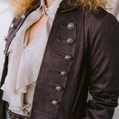 Casaco roxo-escuro com botões metálicos sobre camisa branca com folhos