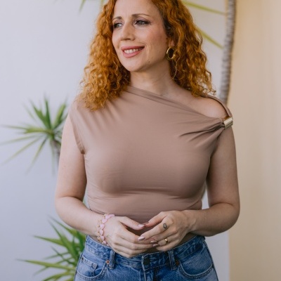 Mulher com camisola bege assimétrica e calças jeans azuis