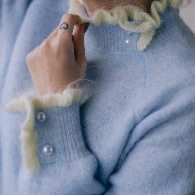 Camisola azul clara com gola e punhos com babados amarelos e botões perolados