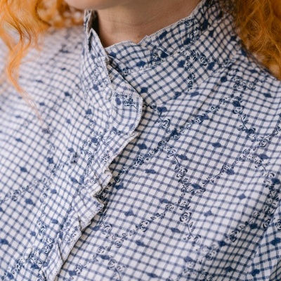 Camisa feminina xadrez azul e branco com bordados florais e gola com babados.