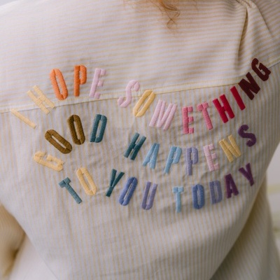 Camisa de riscas amarelas e brancas com bordado colorido nas costas