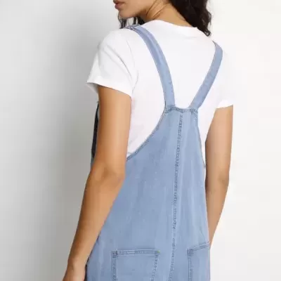Macacão de ganga azul claro com alças largas e bolsos traseiros, t-shirt branca.