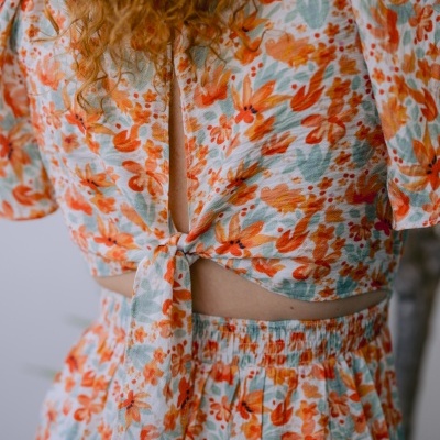 Top e saia com padrão floral em tons de laranja, verde e branco com nó frontal.