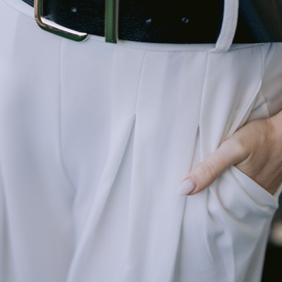 Cinto preto em calças brancas com mão no bolso