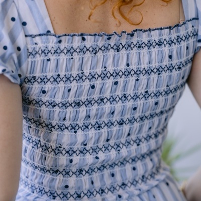 Vestido às riscas azuis e brancas com pontos pretos e detalhes franzidos nas costas.