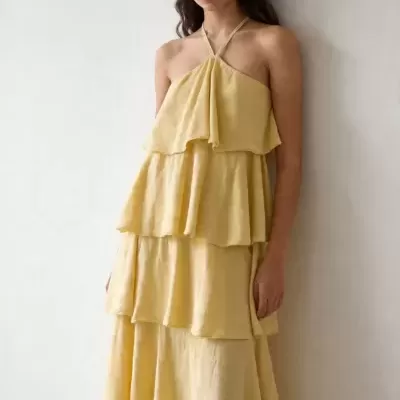 Vestido amarelo com camadas usado por uma mulher com cabelo castanho ondulado