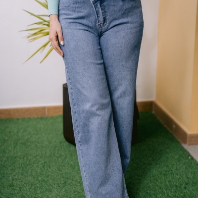 Calças de ganga azuis largas com fecho assimétrico e botas castanhas