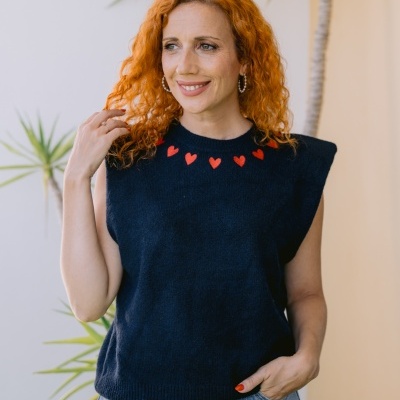 Mulher ruiva com top preto de malha com corações vermelhos e calças de ganga.