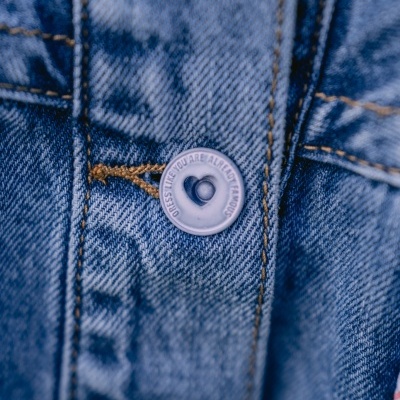 Botão cinza com coração em tecido jeans azul com costura castanha