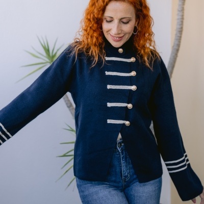 Casaco azul escuro com botões dourados e detalhes em branco nas mangas e frente, jeans azul claro