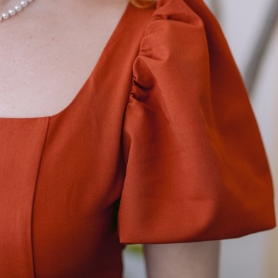 Vestido cor ferrugem com mangas bufantes e colar de pérolas