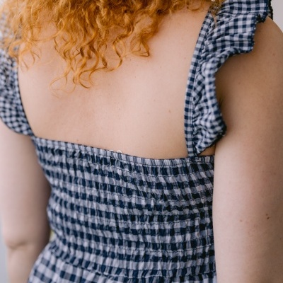 Vestido azul e branco xadrez com alças de folhos visto nas costas.
