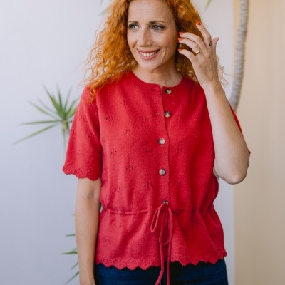Mulher com camisola vermelha de malha com botões e cintura ajustável