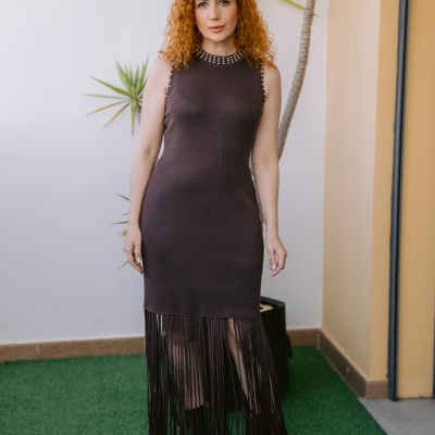 Vestido castanho escuro com franjas e tachas prateadas usado por mulher