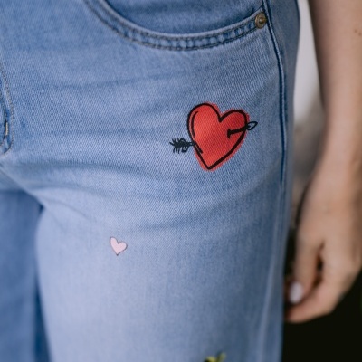 Calças de ganga azuis com desenhos pintados de corações e pássaro