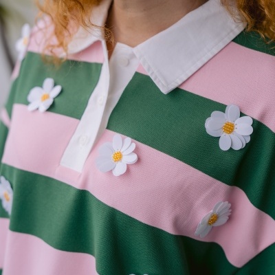 Polo com riscas rosa e verde, gola branca e flores artificiais decorativas