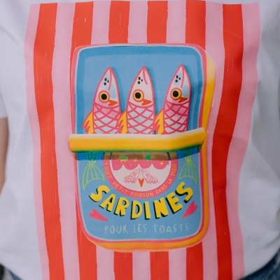 T-shirt branca com estampa colorida de lata de sardinhas estilizada e riscas verticais vermelhas e rosas.