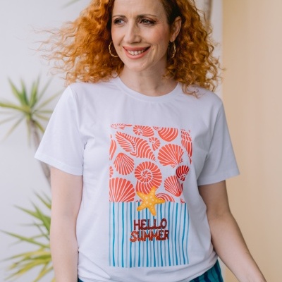 Mulher a usar t-shirt branca com estampa colorida e calças às riscas azuis