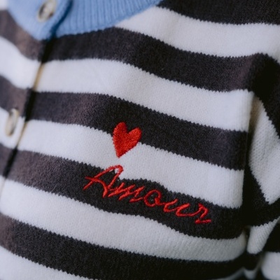 Camisola às riscas preto e branco com gola azul e bordado vermelho de coração e texto.