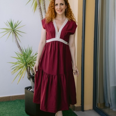 Vestido midi vermelho com renda branca e mulher de cabelo ruivo em ambiente exterior