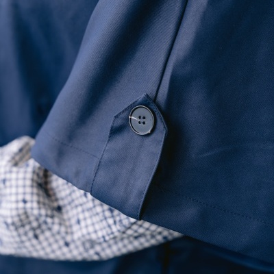 Manga de casaco azul escuro com botão preto e camisa xadrez azul e branco por baixo