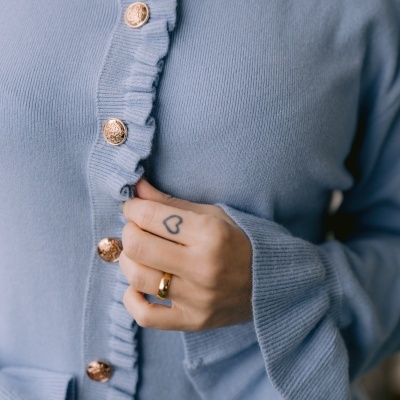 Casaco de malha azul claro com botões dourados e folhos nas mangas