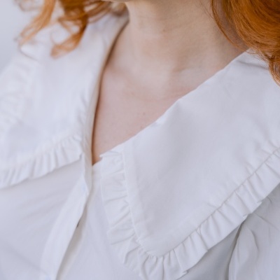 Camisa branca com gola grande folhos e cabelo ruivo