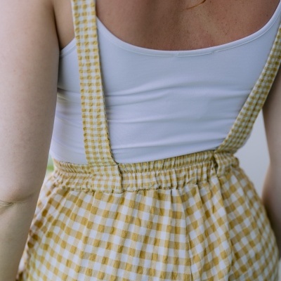 Detalhe de roupa com blusa branca e saia/calças xadrez amarelo e branco visto pelas costas