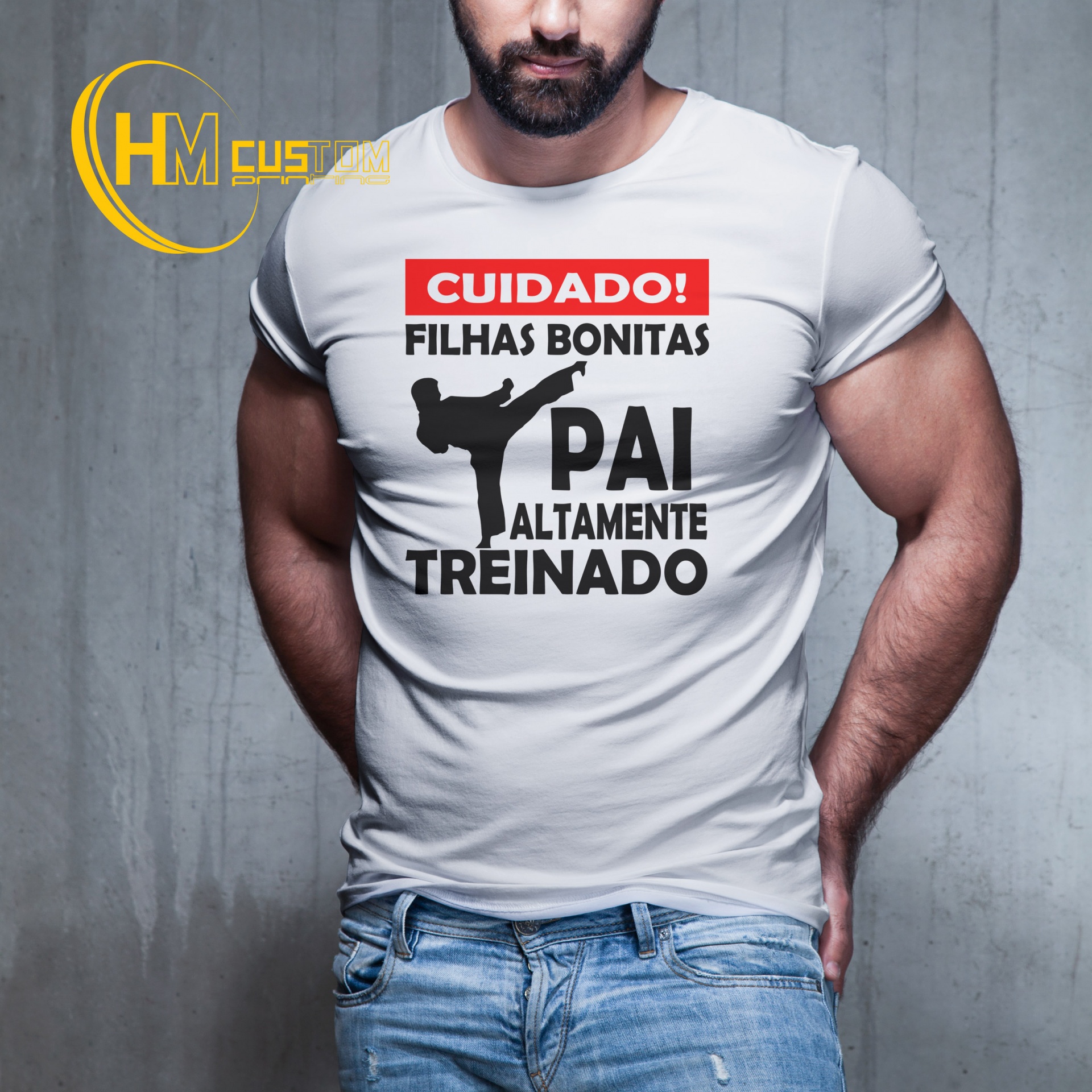 Cuidado Filhas Bonitas Pai Altamente Treinado Homem de barba vestindo t-shirt branca com texto a preto e vermelho em fundo cinzento.