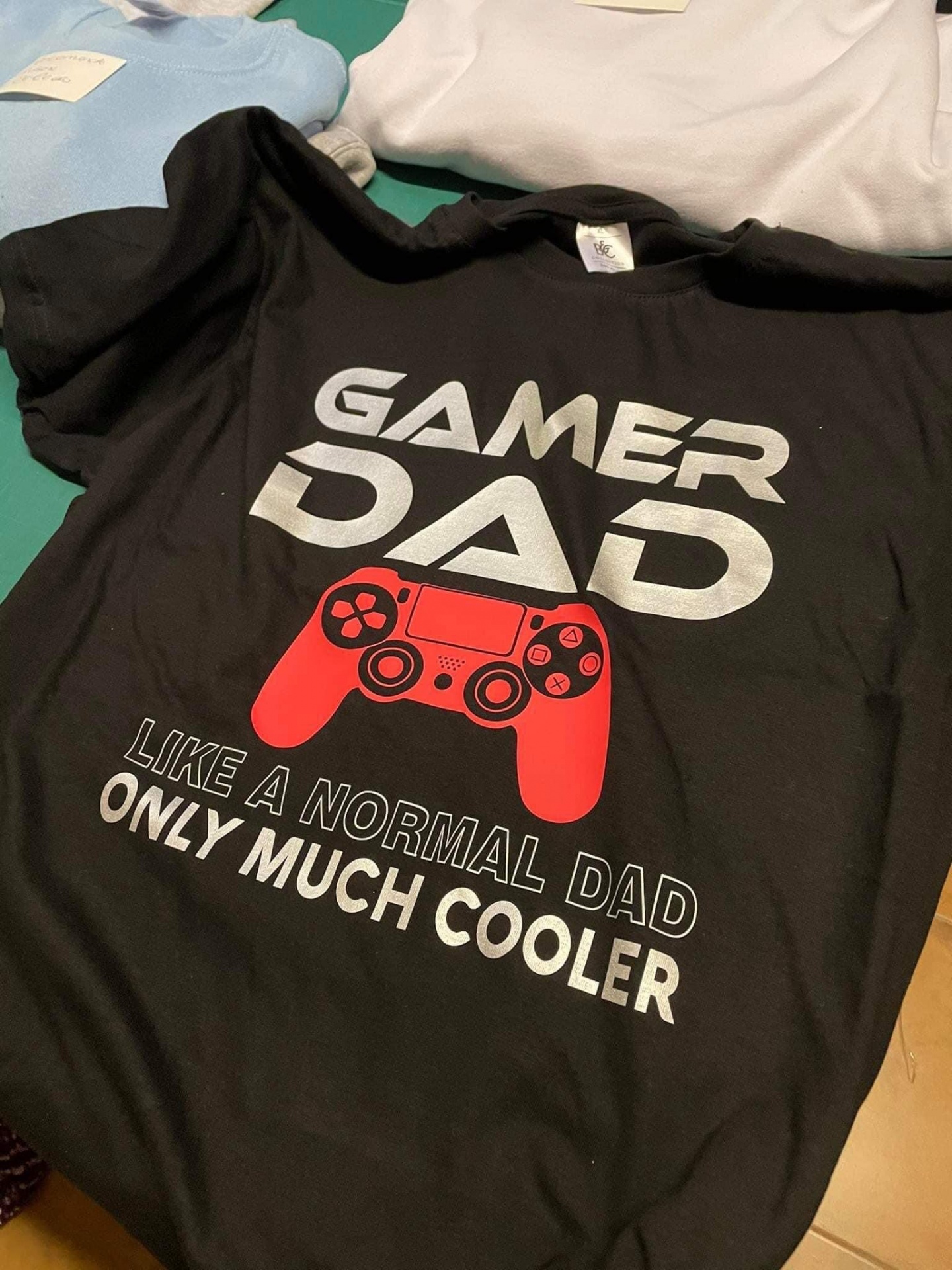 Gamer DAD - Like a normal dad only much cooler T-shirt preta para pai gamer com estampado de comando de videojogo vermelho e texto em inglês.