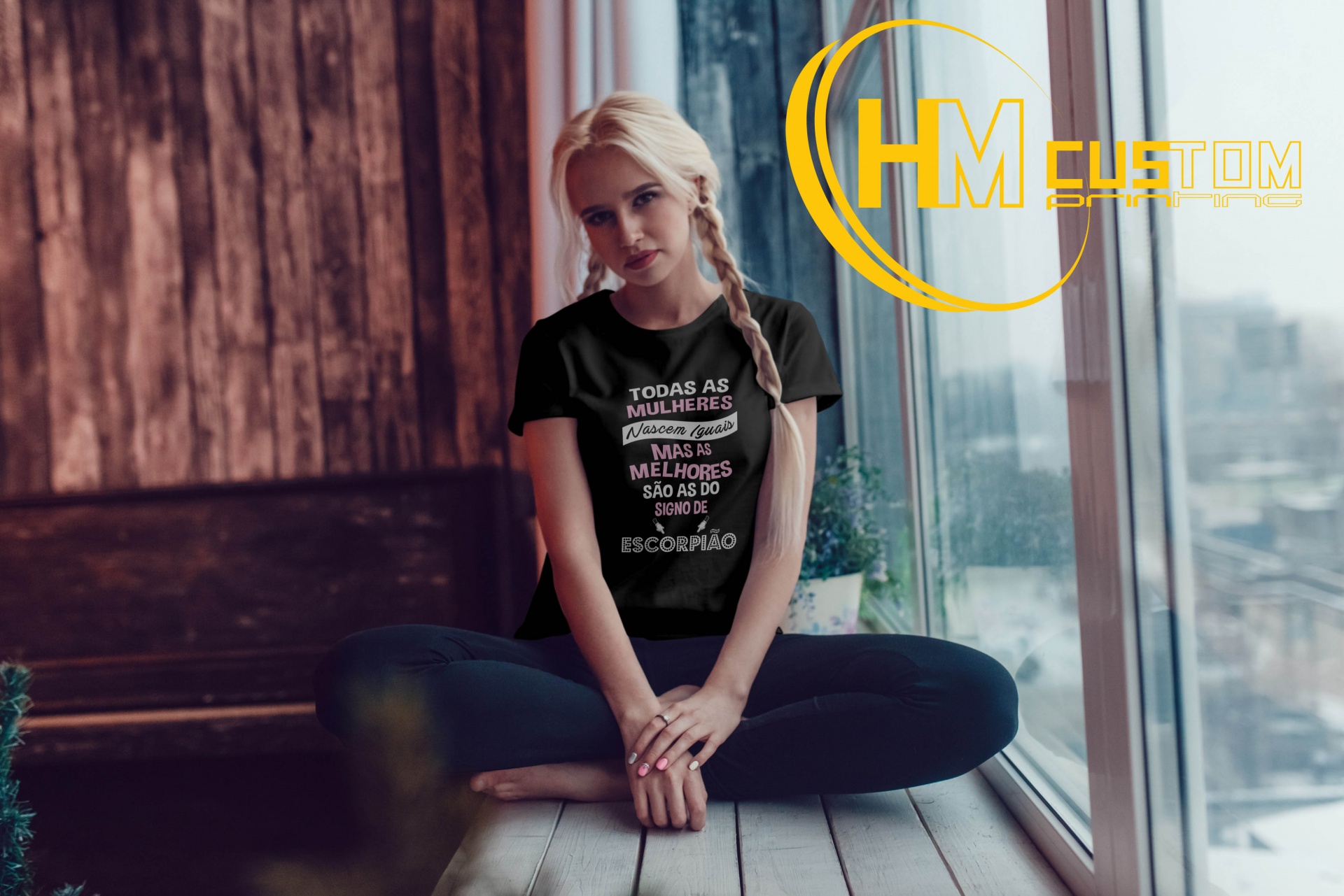 T-Shirt "As melhores Mulheres são do Signo de..." Camisola preta com texto em branco e vermelho usada por mulher sentada à janela