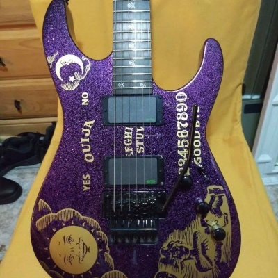 Guitarra elétrica roxa com design de tábua Ouija com texto e imagens na madeira
