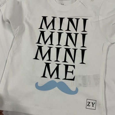 Camisola branca para criança com texto 'MINI MINI MINI ME' e bigode azul