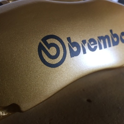 Pinça de travão metálica dourada com logótipo Brembo azul em close-up