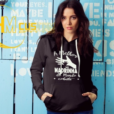 Mulher com sweatshirt preta com capuz e texto branco, frente a parede azul com textos