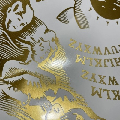 Poster com ilustrações douradas de cabeças e letras em fundo branco