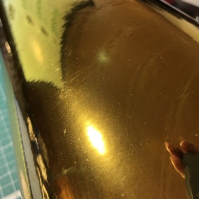 Superfície metálica dourada refletora com mão visível ao lado