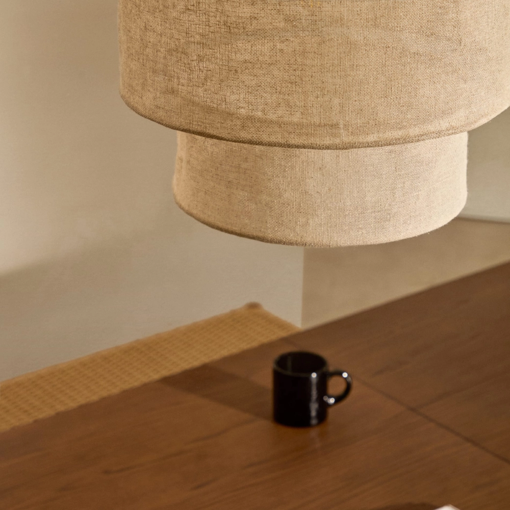 Candeeiro de Teto em Linho Marila Ø40x34 Abajur bege de tecido pendurado acima de mesa de madeira com caneca preta