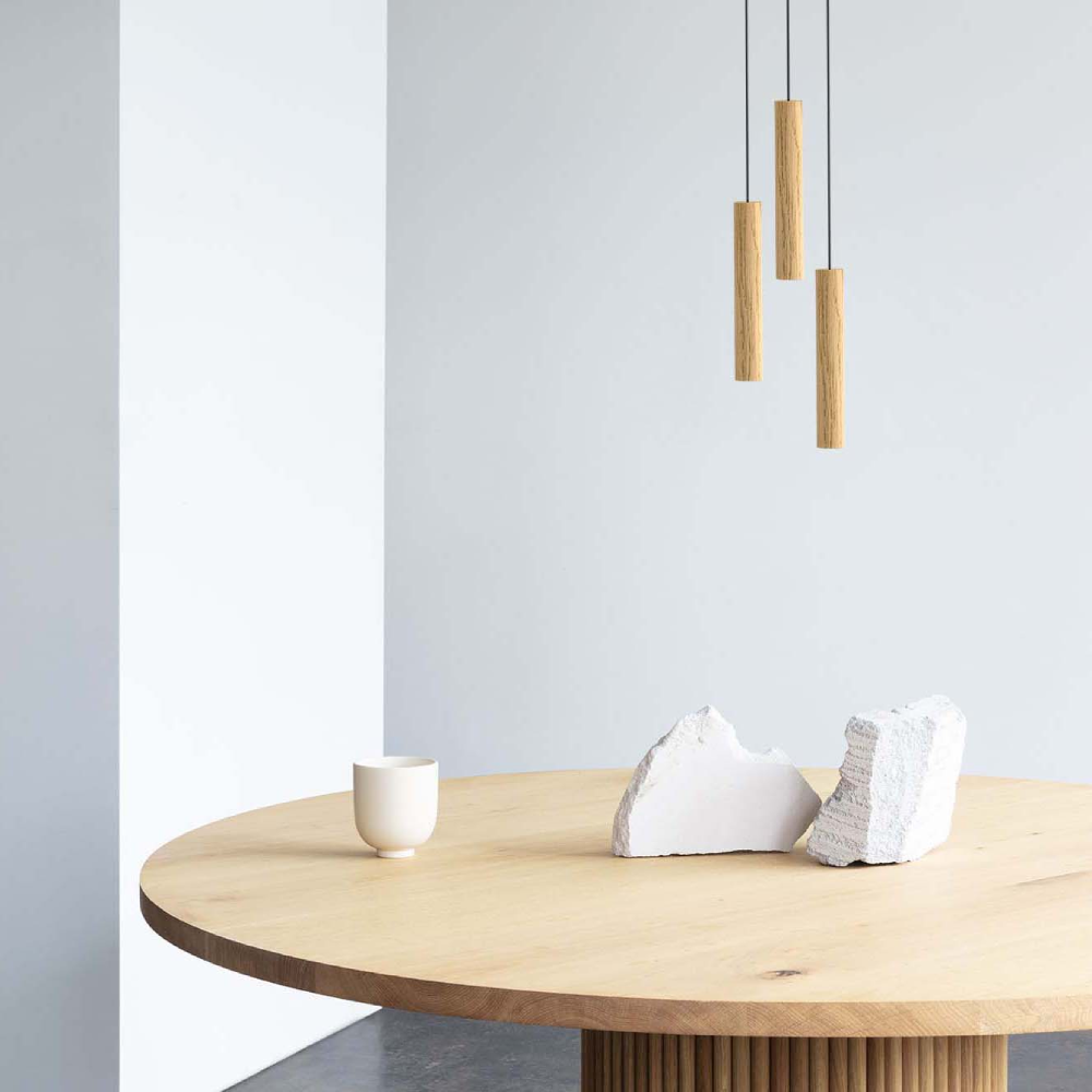 Candeeiro de Teto Chimes Cluster em Madeira de Carvalho Mesa redonda de madeira clara com objetos brancos e pendentes de madeira ao fundo