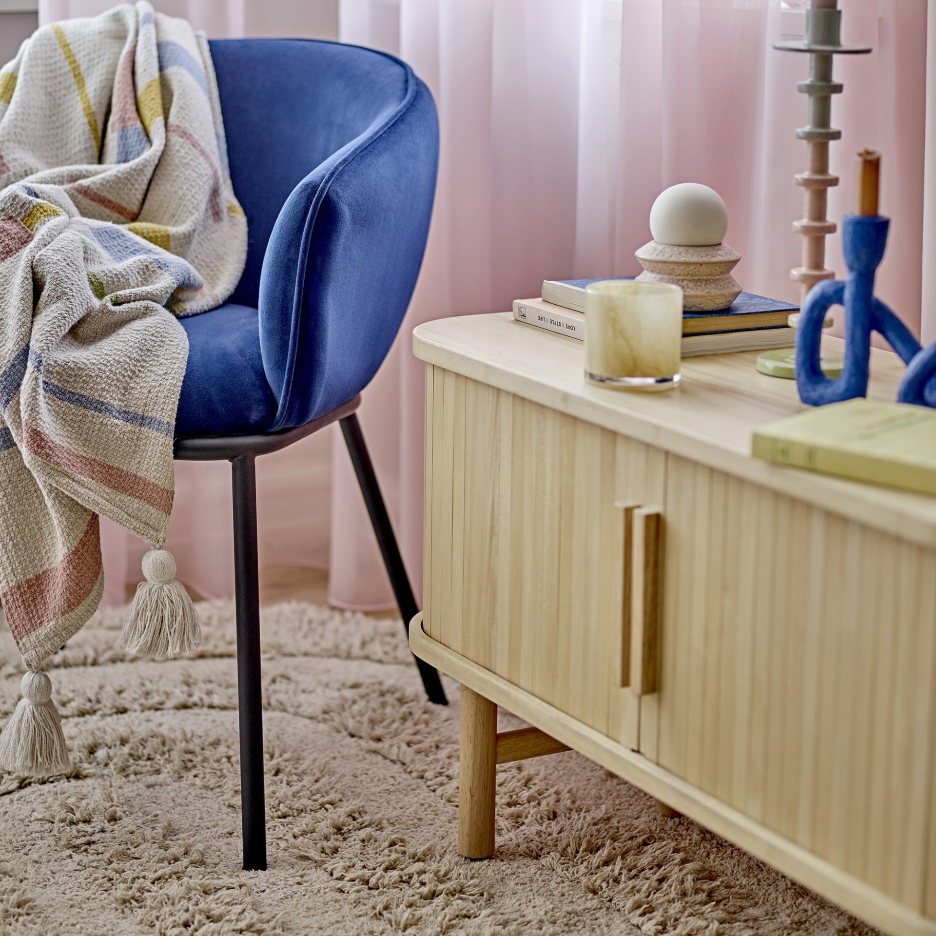 Móvel TV Lex, madeira pinho, 90x50 Cadeira azul com manta às riscas, móvel madeira clara e decoração sobre tapete felpudo bege