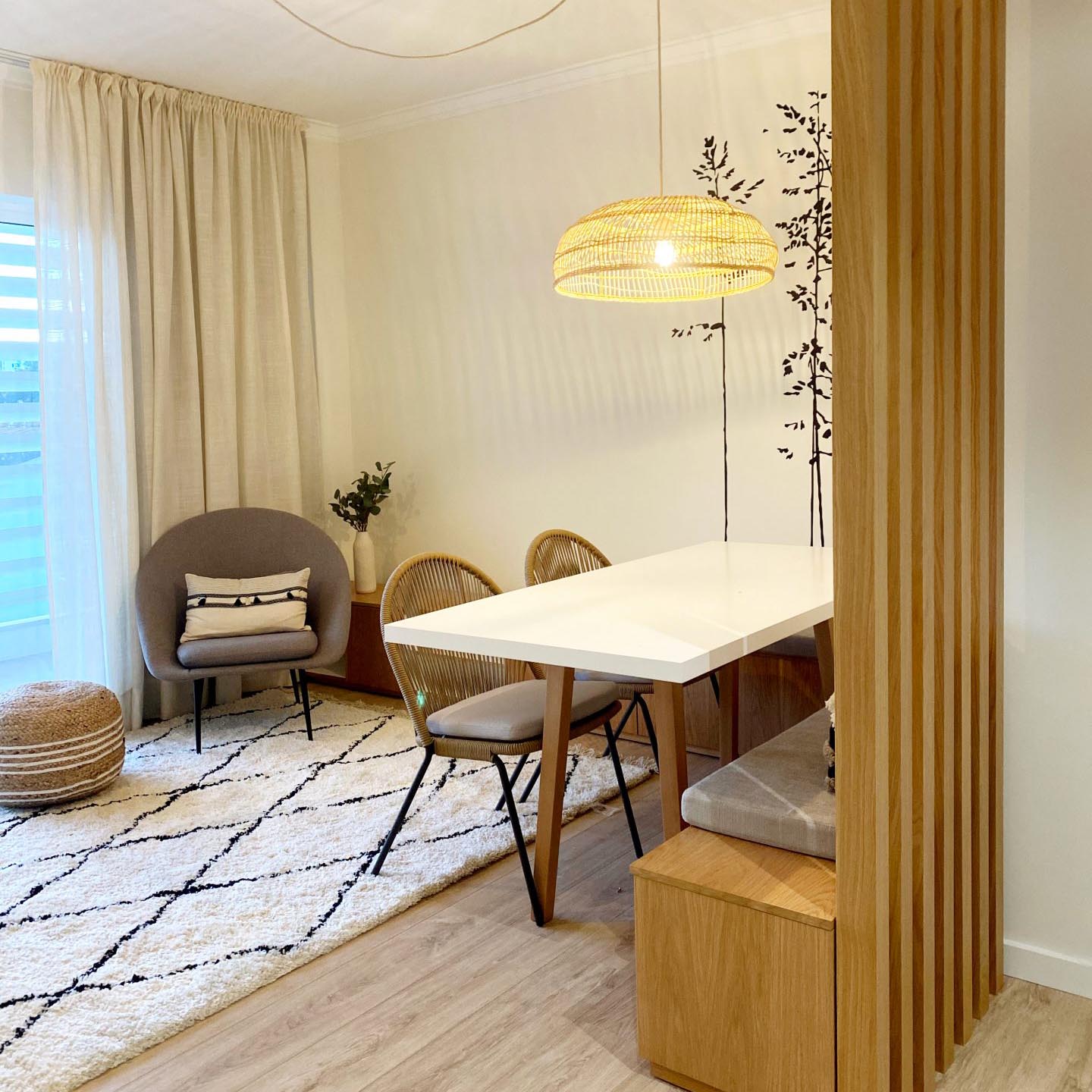 Poltrona Northdam, estofado, cinza Sala com mesa branca, cadeiras, cadeirão cinzento, tapete claro com padrão, abajur trançado e cortinas claras