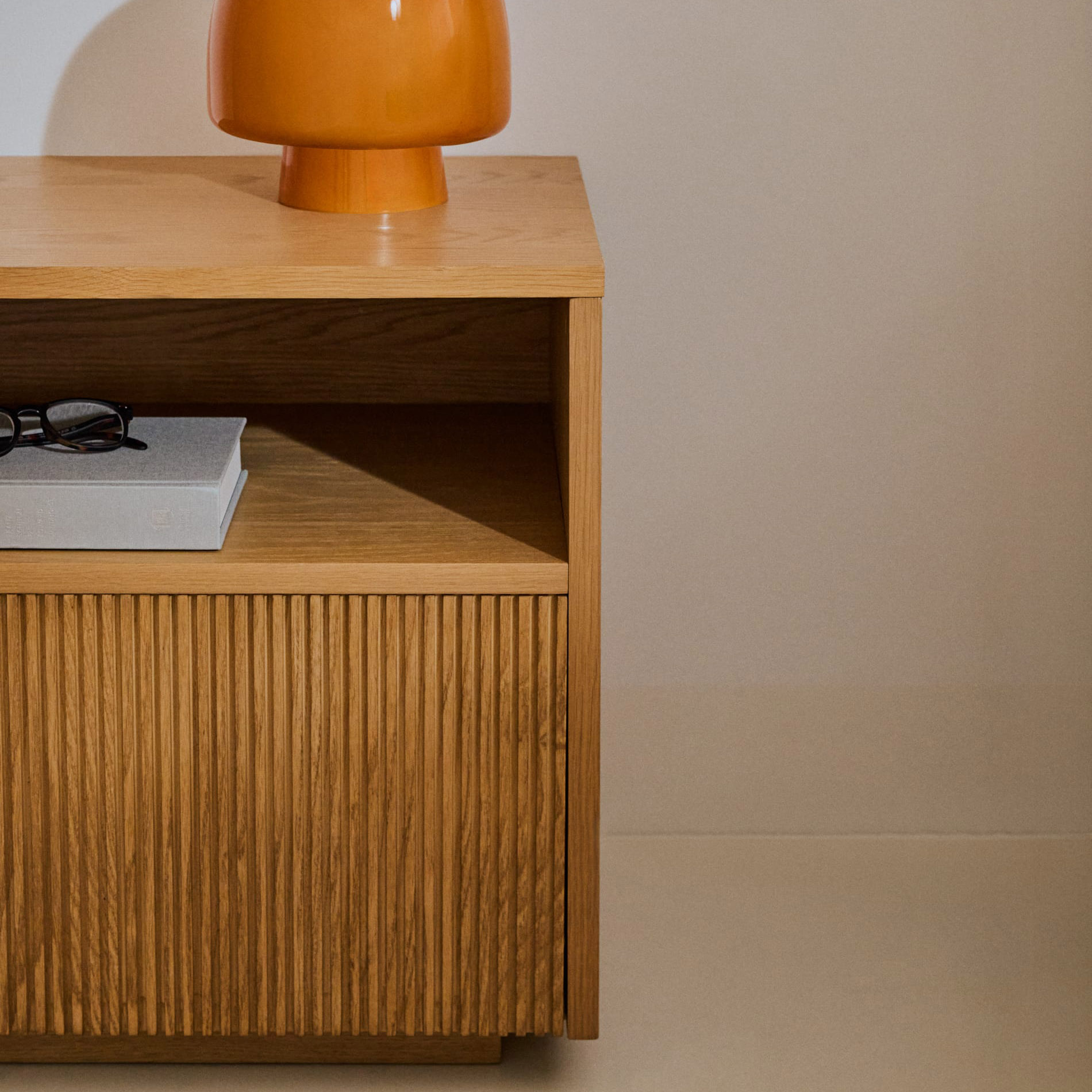 Mesa de cabeceira Helvi, madeira carvalho, 60x52 Móvel de madeira clara com porta ripada e lâmpada laranja em cima