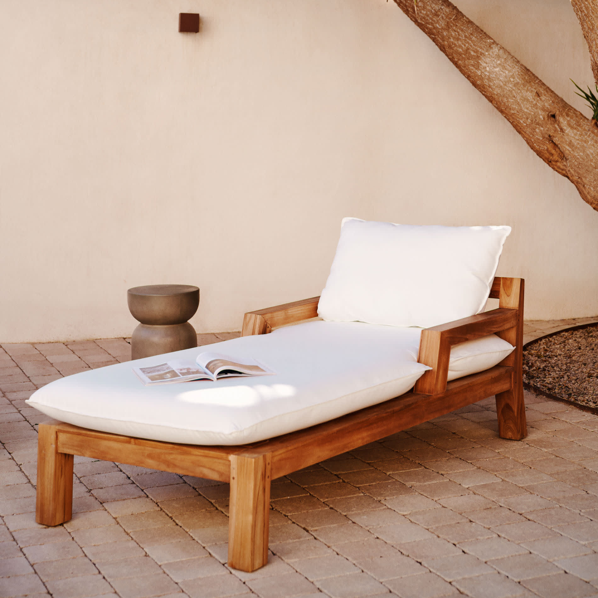 Espreguiçadeira Forcan, exterior, madeira teca Espreguiçadeira de madeira com almofadas brancas junto a árvore e mesa pequena