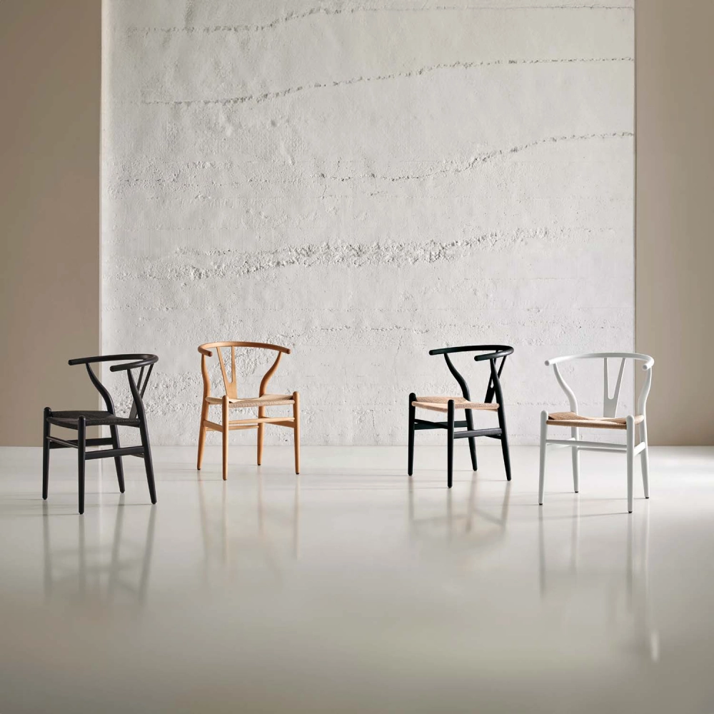 Cadeira com braços em madeira faia Wishbone Quatro cadeiras de madeira em várias cores com assentos em fibras naturais em espaço interior minimalista