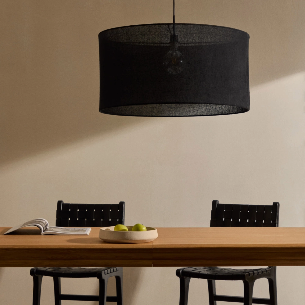 Candeeiro de Teto em Linho Marila Ø80x40 Luminária pendente preta sobre mesa de madeira com cadeiras pretas e frutas